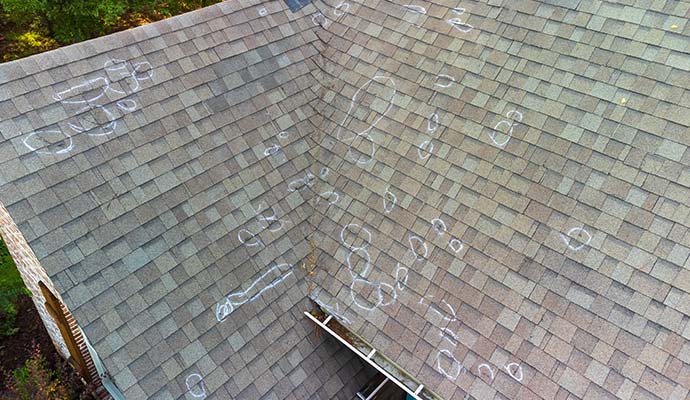 An aerial view of asphalt shingle roof damage, with hail strike marks An aerial view of asphalt shingle roof damage, with hail strike marks