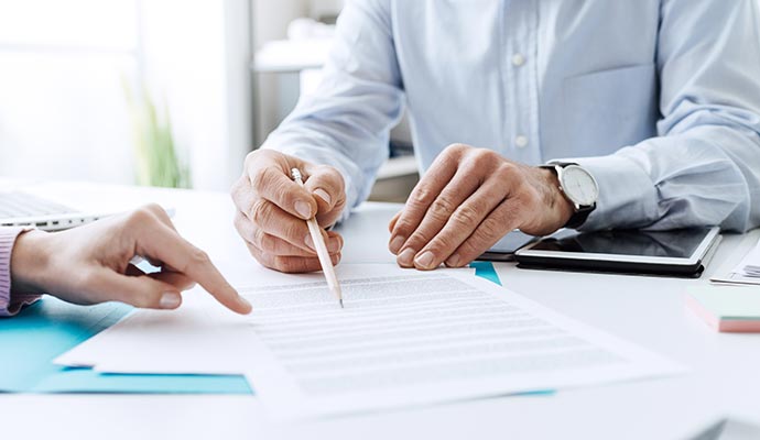 Reviewing a insurance contract Two people reviewing a insurance document at a desk.