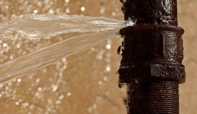 Close-up view of a burst water pipe with water leaking