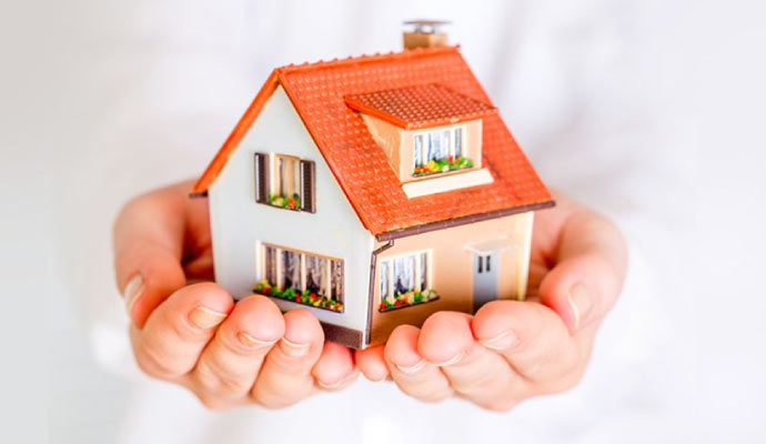 A pair of hands holding a small model house