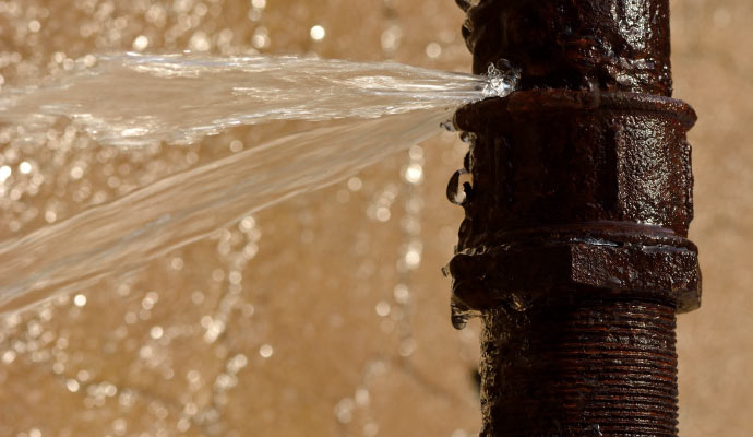 A rusty pipe with water leaking from a crack