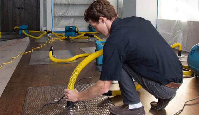 Person cleaning water damage using equipment