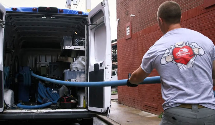 Technician restoring water damage with visible restoration vehicles