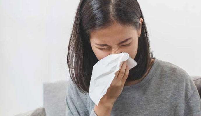 Allergic reaction to mold Woman sneezing into a tissue.